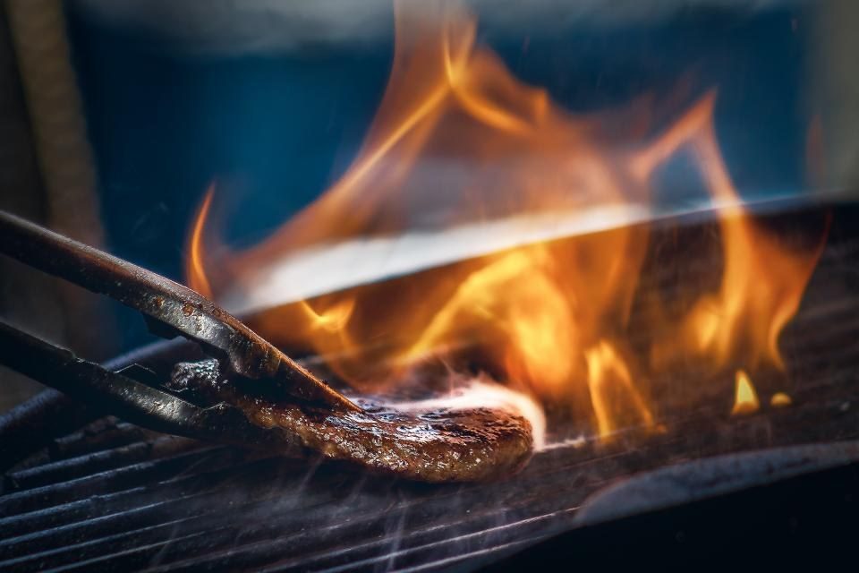 Steak turned over an open flame with tongs